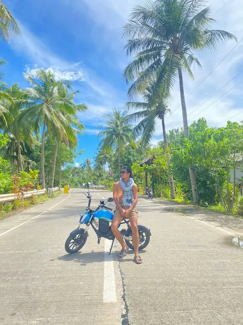 Man sitting on eBike on coconut road, Siargao